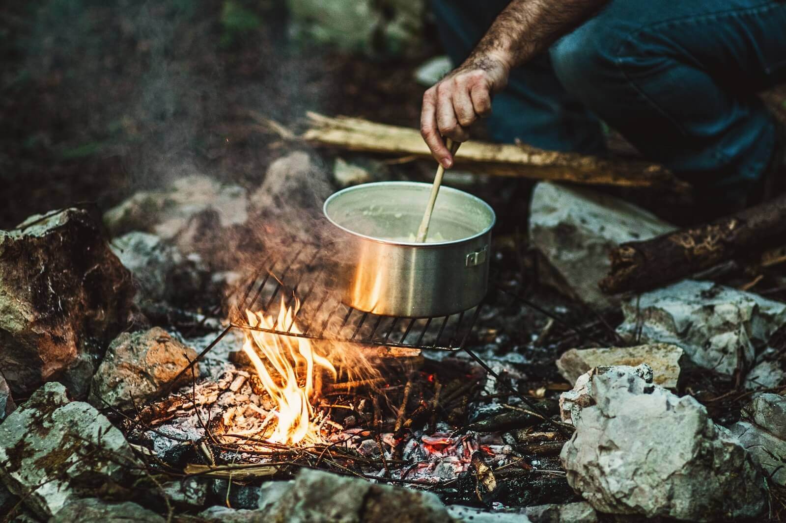 a camper is cooking food on campfire