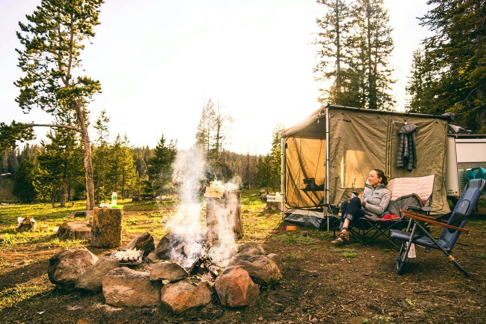 a female camper is sitting in front of her tent