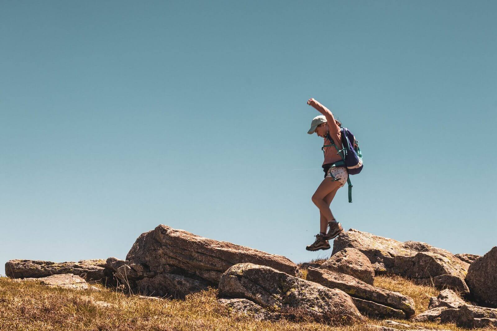 female hiker is climbing rocks on a trail